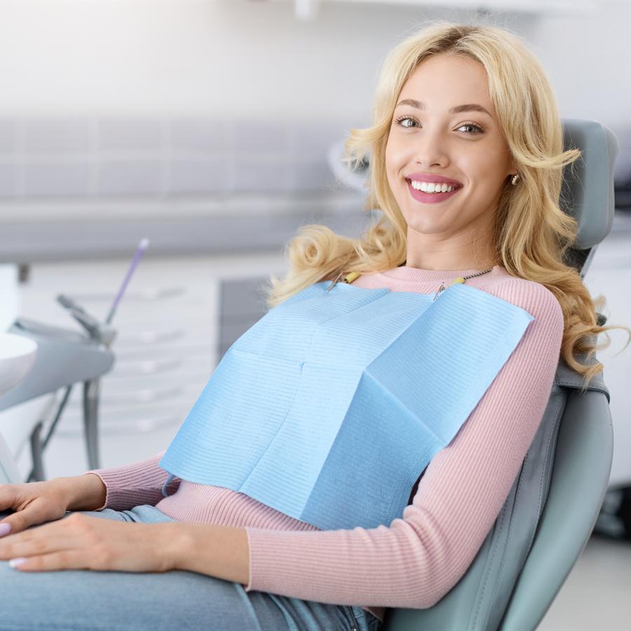 Una paciente recostada y relajada en el sillón, sonriendo, sin instrumental a la vista.